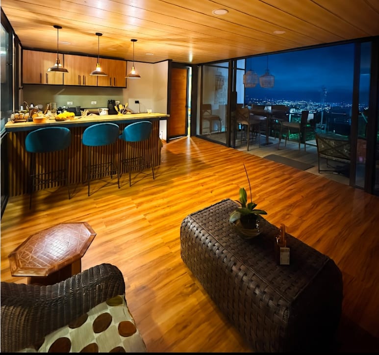 Sala y cocina terminadas de la cabaña Beto, con cielo raso en madera y vista al valle